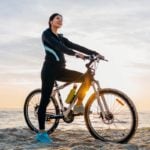 mulher na praia sentada em uma bicicleta