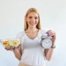 mulher segurando salada e relógio jejum intermitente