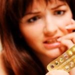mulher preocupada segurando uma cartela de pílula anticoncepcional