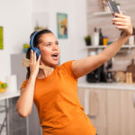 mulher feliz cantando na cozinha e tirando selfie