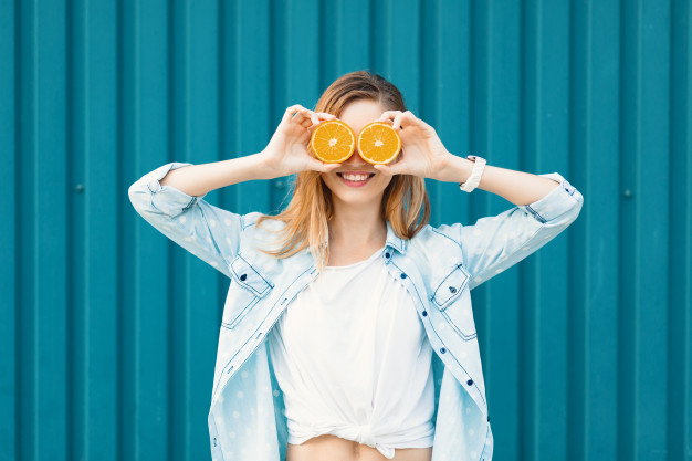 mulher segurando uma laranja que é fonte de vitamina C