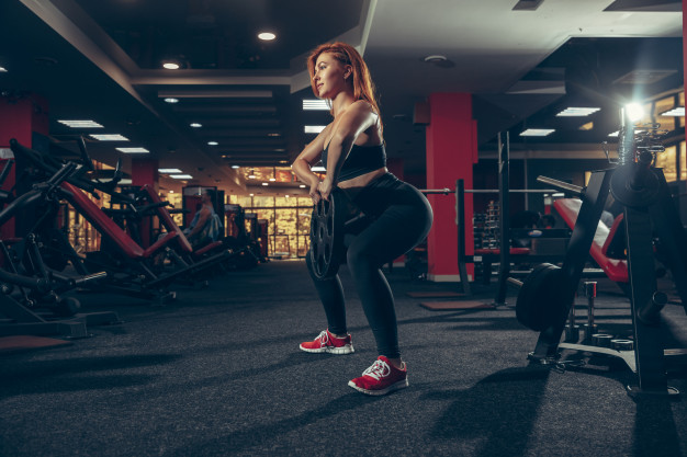 body pump mulher fazendo agachamento com barra