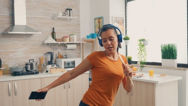 mulher feliz cantando na cozinha