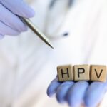 HPV autoteste, aproximação das mãos do médico segurando cubos de madeira com a palavra praticante de HPV apontando com caneta