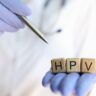 HPV autoteste, aproximação das mãos do médico segurando cubos de madeira com a palavra praticante de HPV apontando com caneta