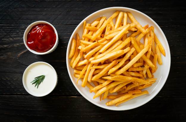 Batatas fritas com ketchup fundo preto. 