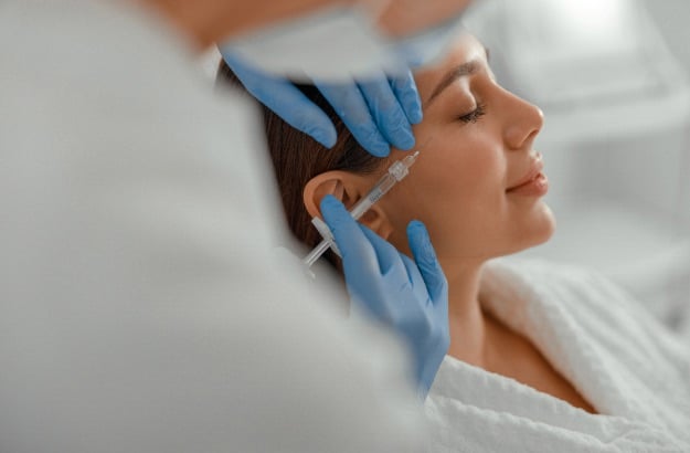 Mulher caucasiana sorridente está realizando procedimento de beleza no spa, salão de beleza, saúde ou clínica de estética. 