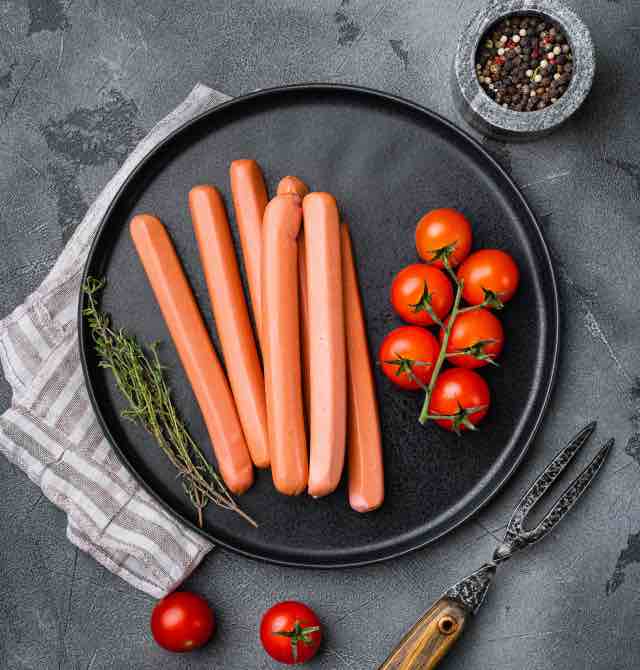 Salsichas alemãs cruas de Frankfurt sobre fundo de mesa  de pedra cinza. 