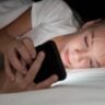 Foto de menina loira usando o celular a noite