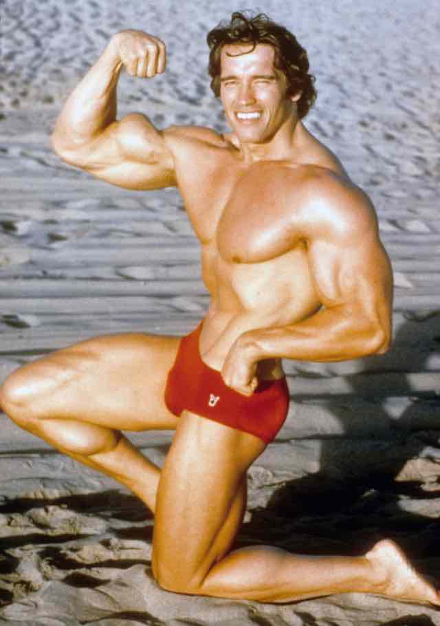Arnold Schwarzenegger de sunga vermelha, exibindo os musculos em 1977. 