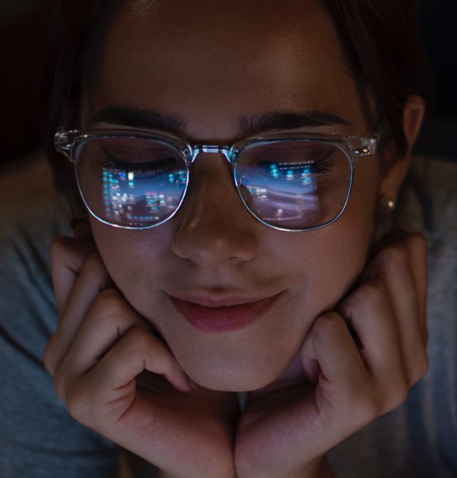 Mulher usando óculos contra luz azul e olhando lap-top