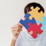 Garoto segurando um quebra-cabeça representando autismo