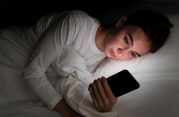 Garota a noite na cama com celular antes de dormir