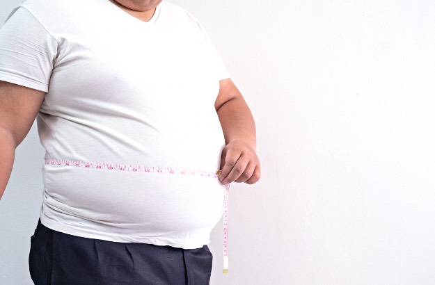 Homem obeso com fita métrica, fundo branco 
