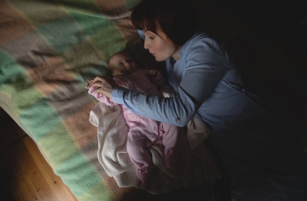 Mãe brincando com seu bebê no quarto 