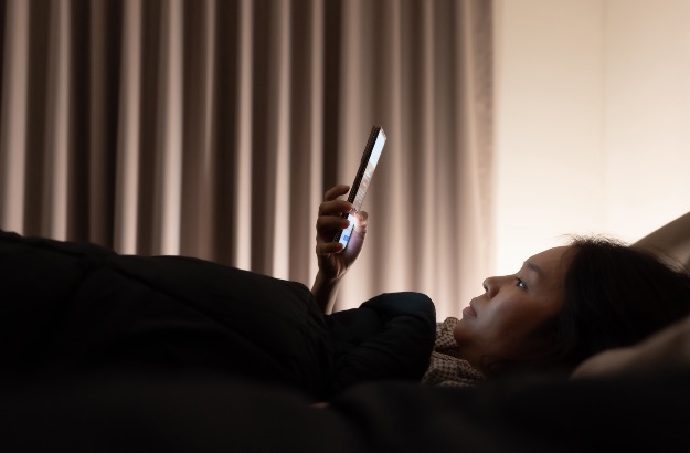 Menina asiática na cama, tarde da noite usando celular antes de dormir 