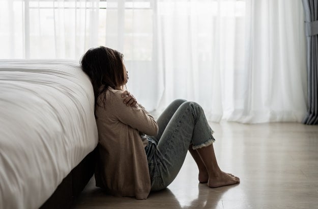 Mulher jovem solitária se sentindo deprimida em seu quarto 