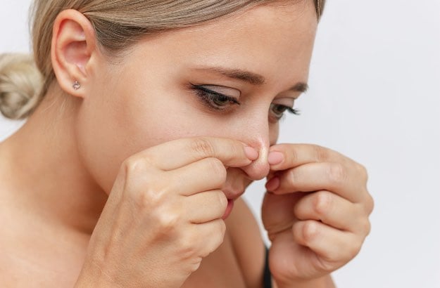Jovem mulher espremendo acne do nariz 