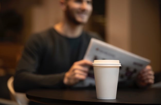 Leitor lendo jornal numa cafeteria 