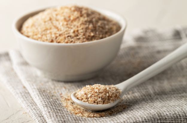 Uma pilha de casca de psyllium em uma colher e uma tigela 