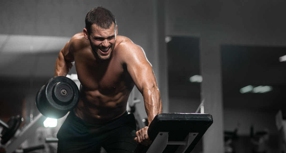Homem atlético treinando na academia para ficar com o corpo definido