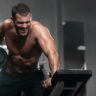 Homem atlético treinando pesado na academia, levantando peso