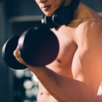 Homem musculoso treinando levantamento de peso na academia para ganho de massa muscular