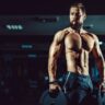 Homem de porte atlético na academia fazendo levantamento de peso para hipertrofia