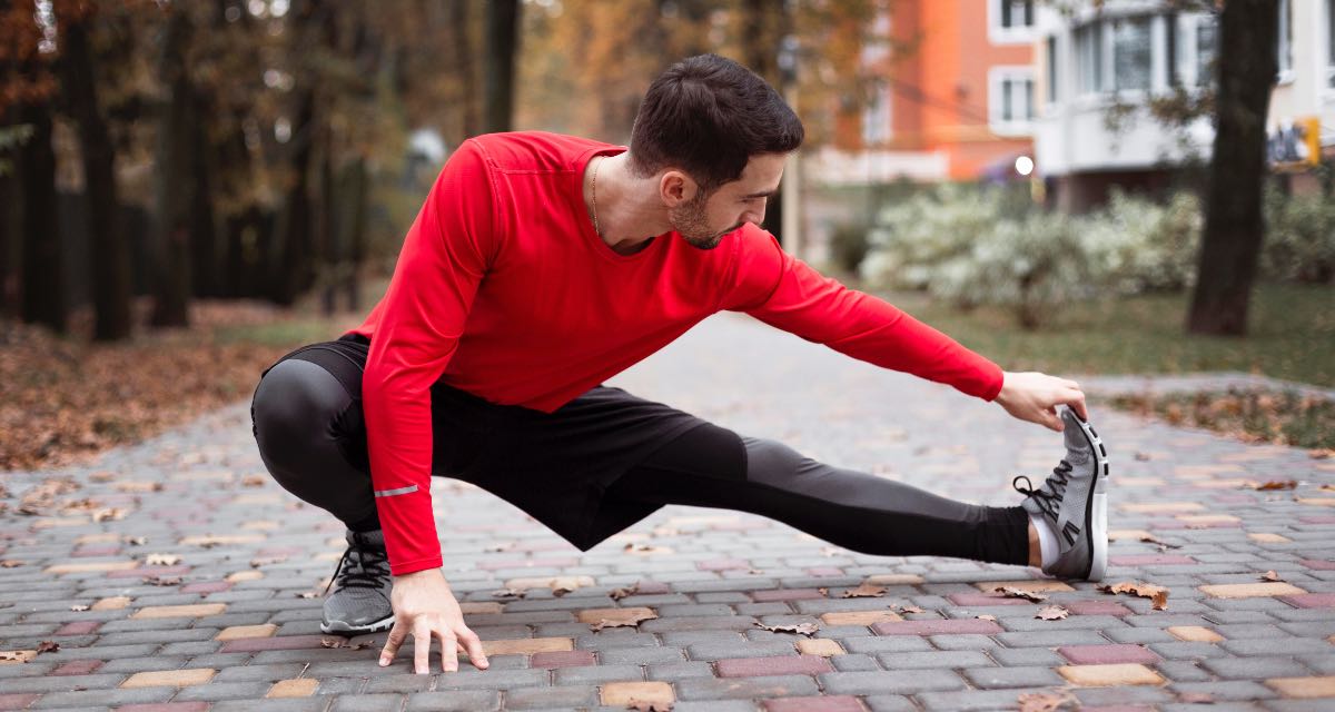 Homem se alongando antes de se exercitar ao ar livre