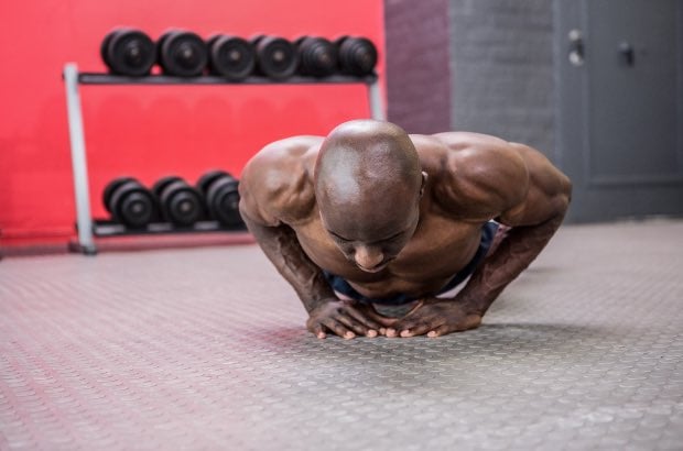 Homem atlético fazendo flexão em academia 