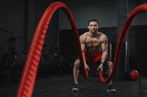 Homem atlético treinando crossfit em academia para definição corporal e ganho de massa magra 