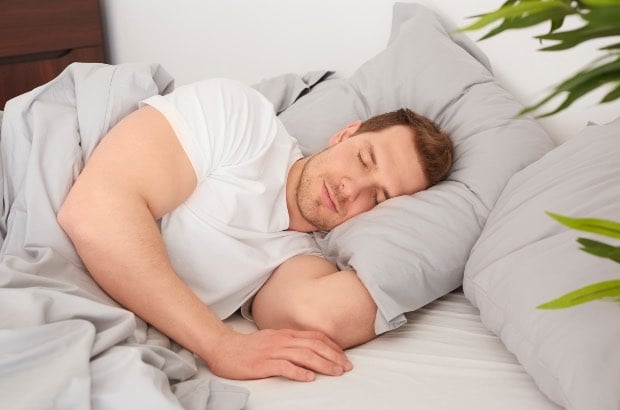 Homem dormindo na cama para uma recuperação muscular adequada