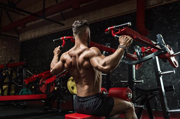 Homem de porte atlético treinando musculação em academia para ganho de massa muscular 