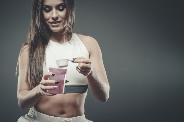 Mulher preparando creatina para treinar em academia 