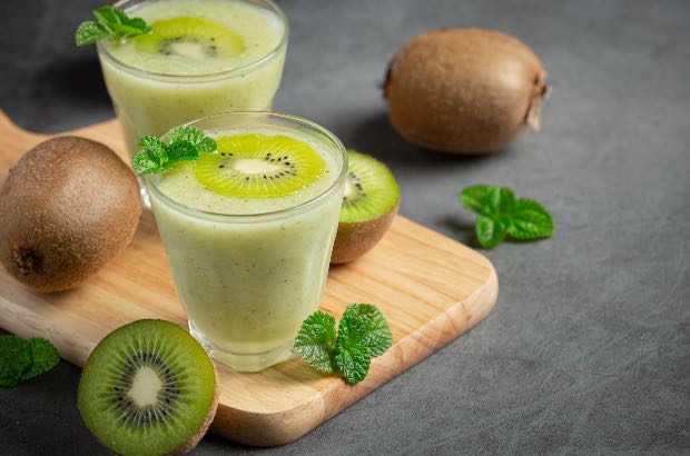 Smoothie de kiwi em cima de tábua de madeira, fundo cinza 