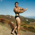 Arnold Schwarzenegger fazendo pose de fisiculturista, exibido seus músculos e boa forma