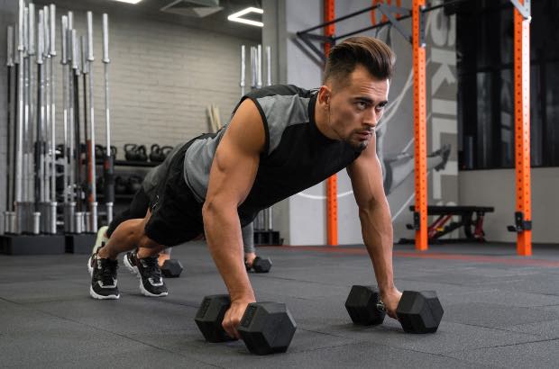 Homem atlético fazendo exercício Renegade Row com flexão e torção