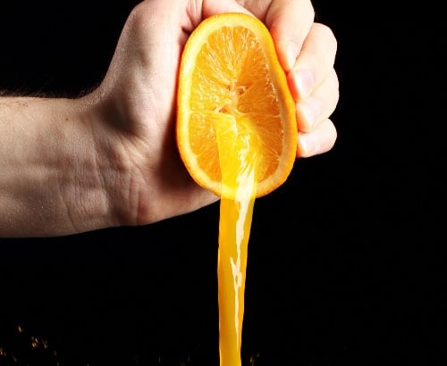 Homem espremendo laranja para fazer suco 