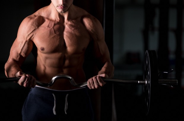 Homem musculoso com veias saltadas treinando bíceps na academia 