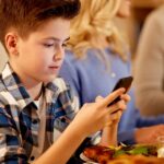 Criança comendo em frente ao celular