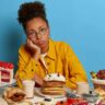 Jovem rodeada de comidas ricas em açúcar