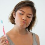 Mulher com escova de dente nas mãos