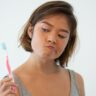 Mulher com escova de dente nas mãos